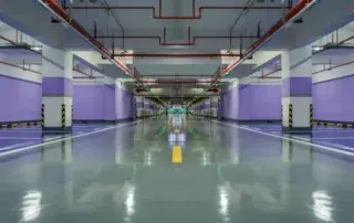 A large warehouse or factory floor with smooth, glossy epoxy flooring marked with safety lines.
